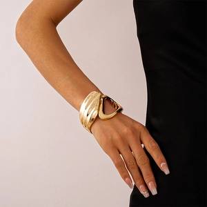 Detail view of bold metallic gold geometric bracelet on wrist with glossy finish