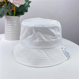 Detailed close-up of white cotton bucket hat featuring a minimalist black text woven label