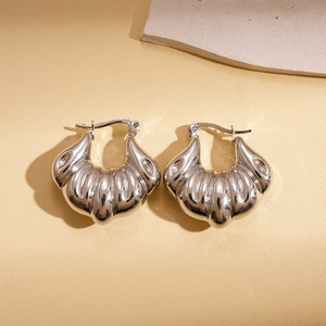 Detailed close-up of silver shell-shaped metallic hoop earrings with textured finish