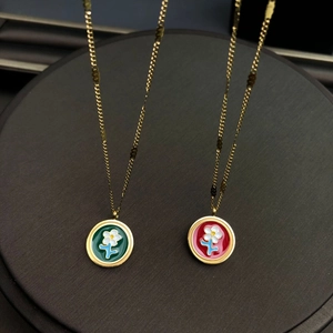 Détail de pendentifs fleurs en émail rouge et vert sur des chaînes en métal doré