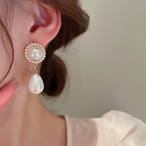 Dettaglio di orecchini vintage con perle e finitura dorata indossati da una modella