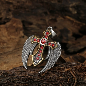 Titanium steel cross necklace with angel wings and red gemstones on wood backdrop
