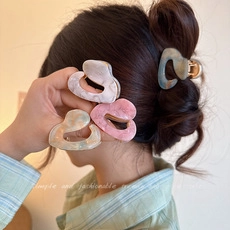 Detailed view of hair claws with marble texture in pink, cream, and grey blue shades