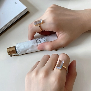 Detail shot of two gold rings with large rectangular clear gemstones on model hands