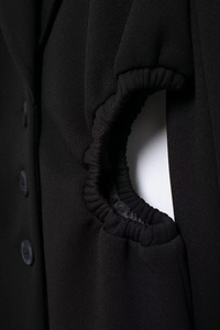 Detail shot of black blazer showing side cutout design with elastic waistband structure