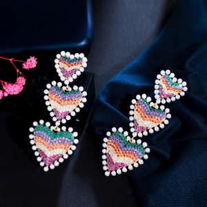 Détail de boucles d'oreilles cœur arc-en-ciel avec zircons et bordure en perles
