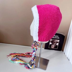 Detail of colorful hand-woven tassels and pink plush faux shearling earflap hat