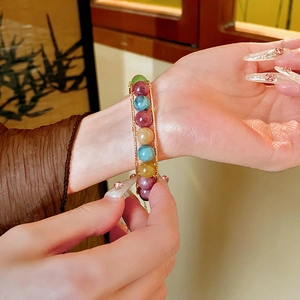 Detailed view of handmade beaded bracelet with tiger eye and quartz on a person's wrist