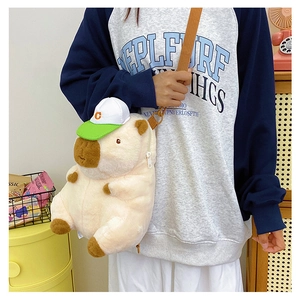 Detail view of cute Capybara plush crossbody bag with green cap worn by a model