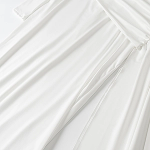 Detail of elegant white long dress showing smooth silky fabric and flowing draped hemline