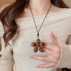 Macro detail of oval floral resin pendant on black cord worn by a female model