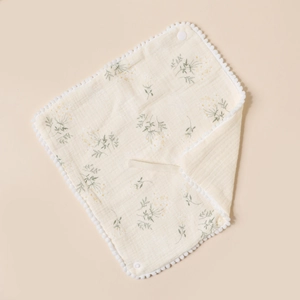Macro shot of cotton baby bib with vintage floral prints and pom-pom trim detail