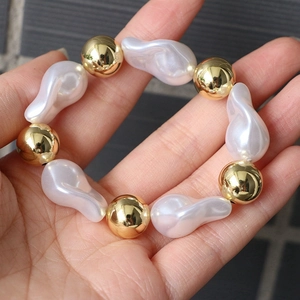 Handheld view of elegant adjustable bracelet with baroque pearls and golden beads
