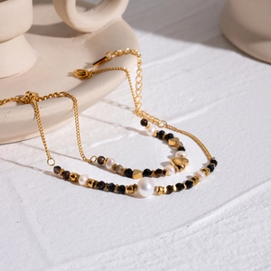 Women's beaded heart bracelet with white pearls and black faceted stones in gold finish