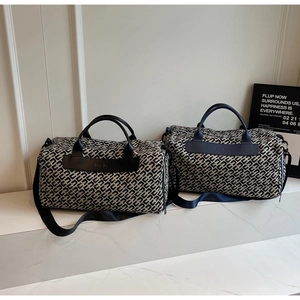 Dettaglio di borse da viaggio in tessuto jacquard con manici in pelle su marmo