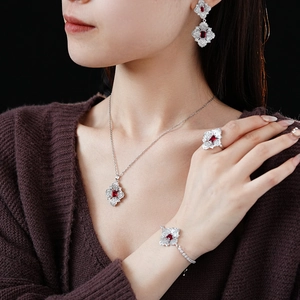 Detailed close-up of a flower jewelry set with red gemstones on a model in dark background