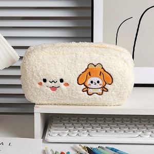 Dettaglio dell'astuccio in peluche color crema con ricamo a forma di cucciolo sulla scrivania