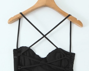 Detail of black dress featuring intricate cross-strap design and textured floral fabric
