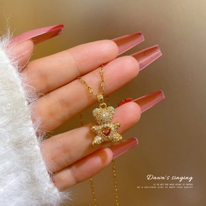 Macro shot of gold teddy bear pendant with micro-pave zircons and a red heart gemstone