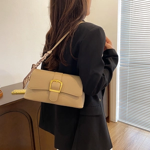 Detail of beige lychee texture shoulder bag with gold buckle and silk scarf on strap