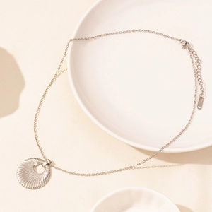Detail shot of a minimalist silver stainless steel necklace with a sunburst round pendant