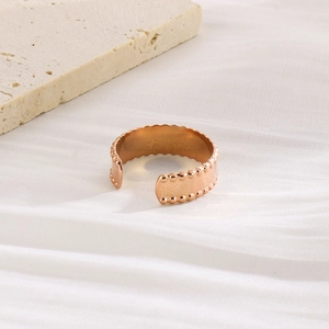 Detail of rose gold open C-ring with polished geometric beads on a minimalist stone base