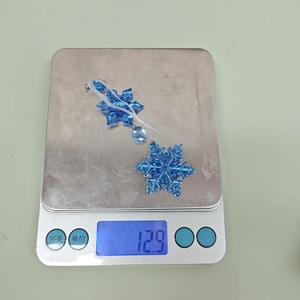 Macro shot of 12.9g ice blue acrylic snowflake ornament hanging with white ribbon