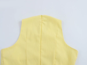 Dettaglio del tessuto giallo plissettato con cerniera posteriore invisibile su un abito