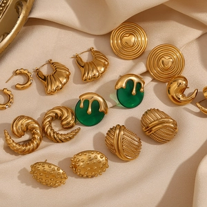 Flat lay of vintage gold-plated earrings with emerald details on silk fabric