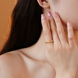 Close-up of gold bamboo ring with micro-paved zircons worn on hand in warm light