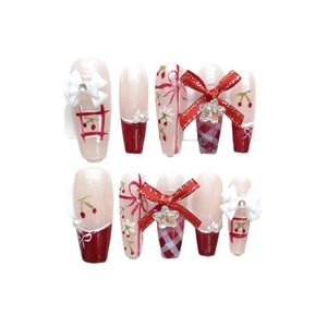 Handmade Christmas press-on nails with red bows, cherry patterns, and plaid designs