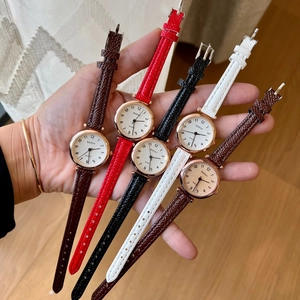 Multiple colors of women's quartz watches with leather straps held in one hand