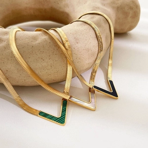 Detailed macro view of V-shaped gold snake bone necklaces with malachite and shell inlays