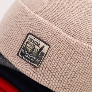 Close-up of ribbed knit texture and vintage denim label on various colored beanies