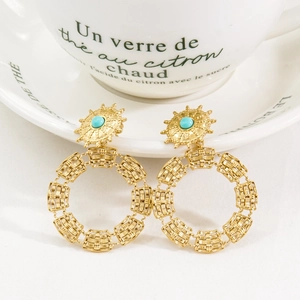 Detail of bohemian sunburst earrings with blue stone inlay and woven gold circle drops