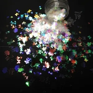 Macro shot of 3mm butterfly and clover iridescent glitter pouring from a clear jar
