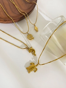 Detailed view of gold ocean-themed pendants featuring sea turtles and shells on soft background