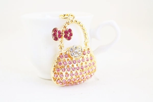 Close-up of golden handbag keychain featuring pink rhinestones and a bow ornament