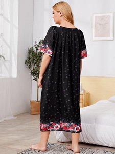 Back view of a loose black nightgown featuring vibrant floral prints in a cozy bedroom