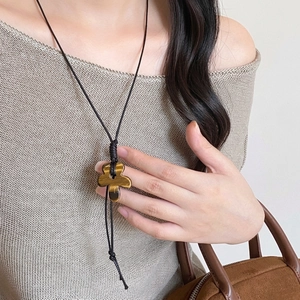 Detail of tiger eye flower pendant with black woven cord necklace on a sweater
