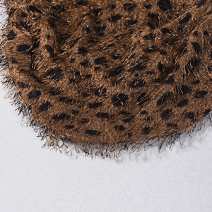Vue macro du béret léopard en fausse fourrure montrant la texture douce et les coutures
