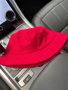 Detailed texture of a red corduroy bucket hat displayed on a car dashboard
