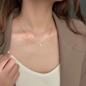 Elegant gold heart pendant necklace on model wearing a white top and beige blazer