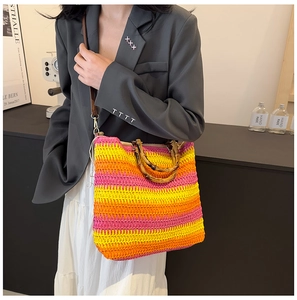 Detail of colorful woven straw tote bag with natural bamboo handles and leather strap
