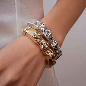 Macro detail of irregular lava texture on gold and silver metallic open bangles
