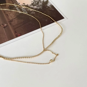 Minimalist gold beaded thin chain necklace on a French vintage postcard background
