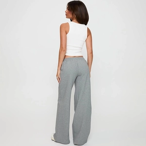 Vue arrière d'une femme en débardeur blanc et pantalon décontracté gris à jambes larges