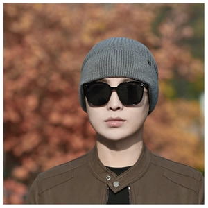 Detail of grey ribbed knit beanie featuring small metal brand tag and premium texture