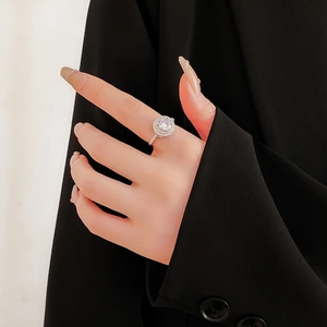 Close-up of a silver open ring featuring a large round zircon and pavé-set diamond band