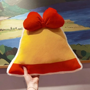 Close-up of yellow bell-shaped plush pillow with large red bow and white faux fur trim